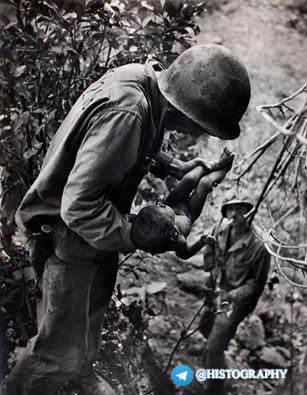 تلاش سرباز آمریکایی برای نجات دادن کودک ژاپنی از زیر آوار جنگ .   عکاس: یوجین اسمیت
